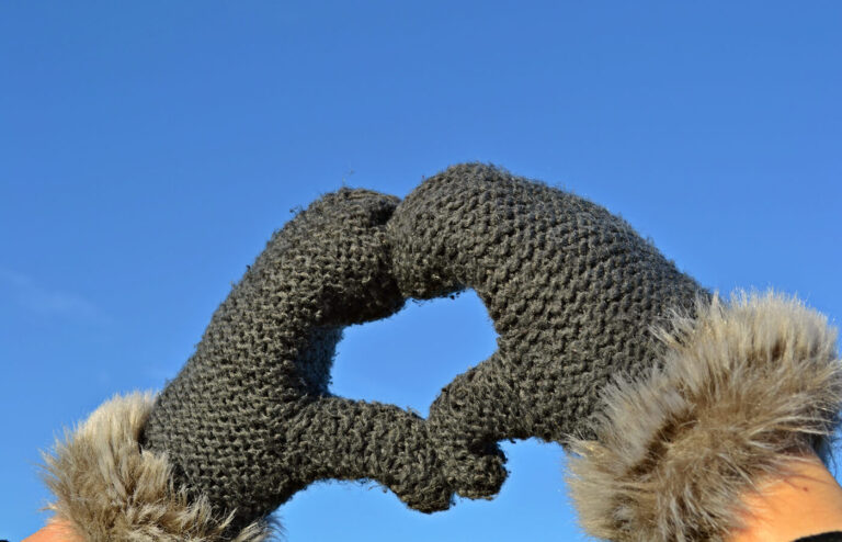 Hands wearing mittens making the shape of a heart