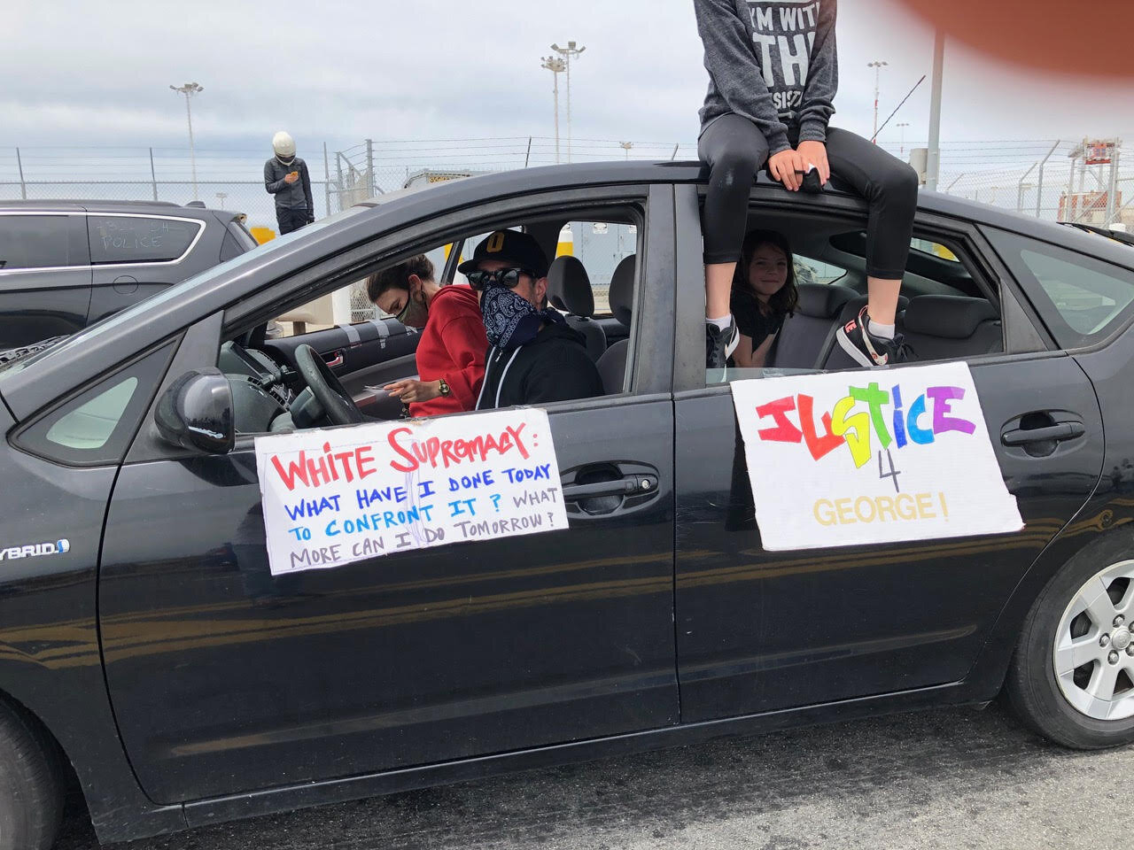 Car protesters with signs that read: White Supremacy: What have I done today to confront it? What more can I do tomorrow? and Justice 4 George!