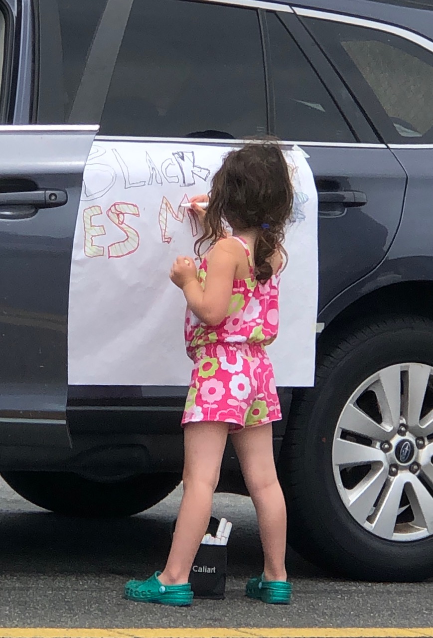 A young person makes a BLM poster for a car demonstration.
