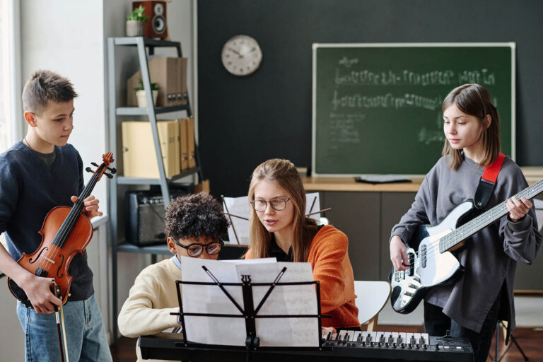 Students gathered around a teacher learning music.