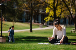 A student reads a book on the grass