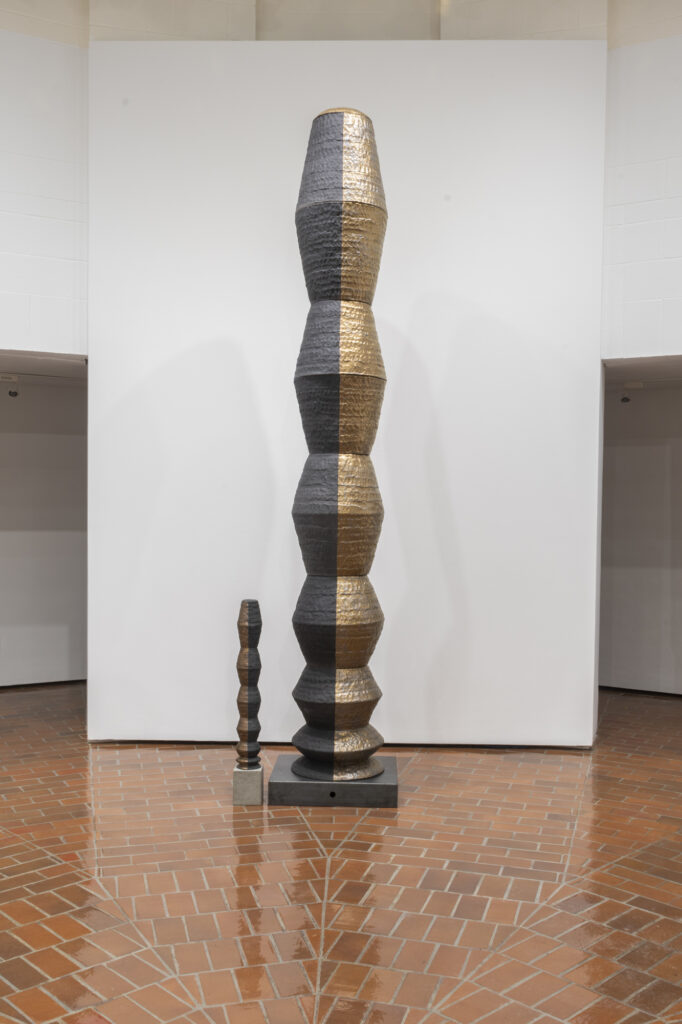 Stacked rounded geometric column sculpture in dark material.