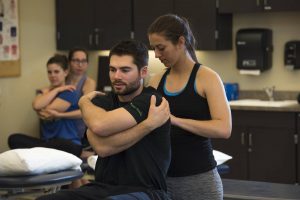 One student adjusts the back of another student