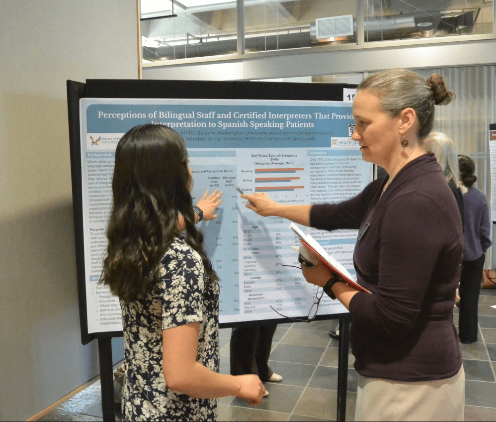 Anna Tressider looks at a presentation poster with a student