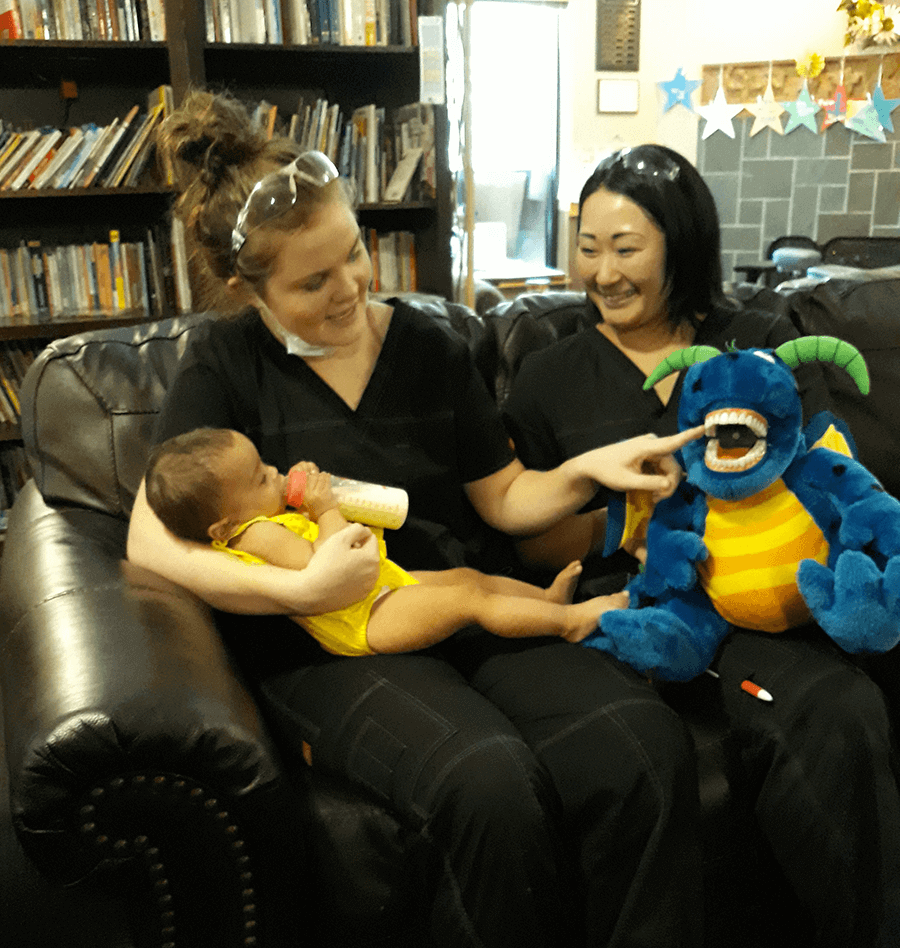Students show a toddler a toy with teeth