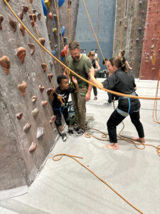 Student assisting a participant on the climbing wall.