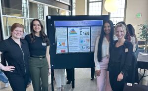 Four students in front of their presentation at the scholarly works