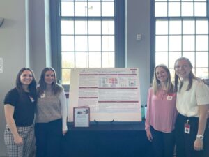 Four students in front of their presentation at the scholarly works