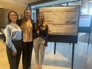 Three students in front of their presentation at the scholarly works