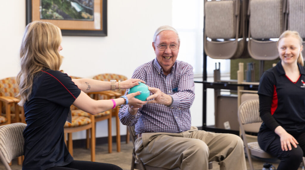EWU exercise science students do a mobility exercise with an elderly man