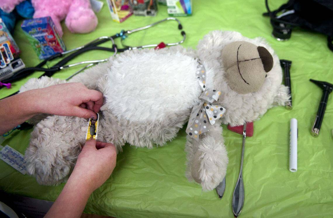 A child puts a bandaid on a teddy bear