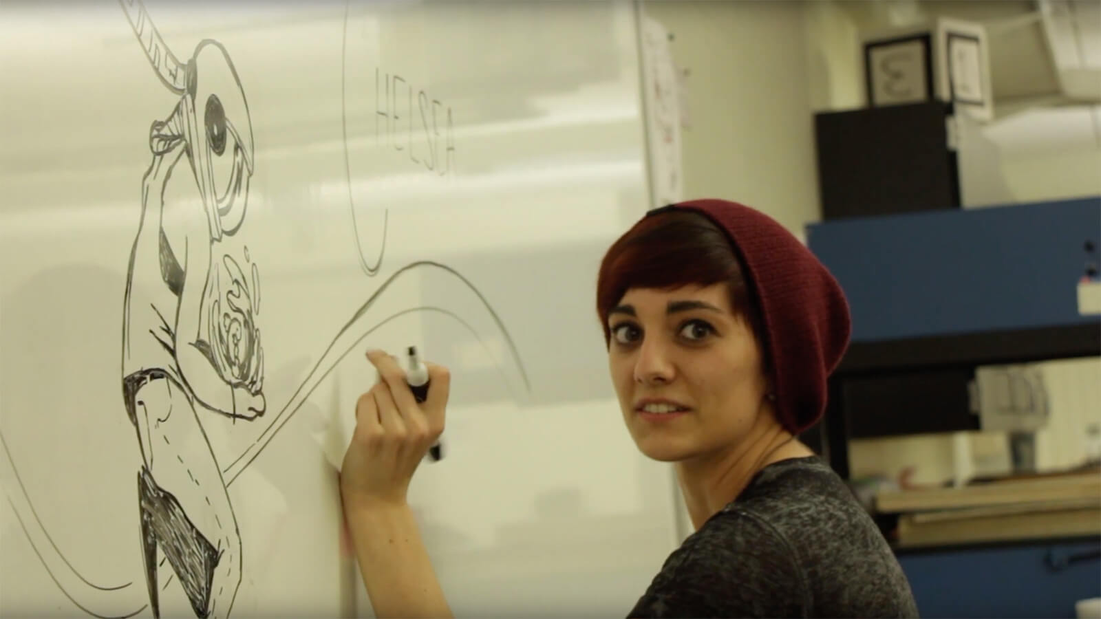 A design student draws an illustration on the whiteboard