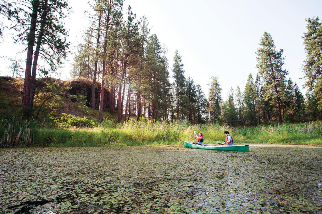 Two students sit in a kayak, doing research at Turnbull National Wildlife Refuge