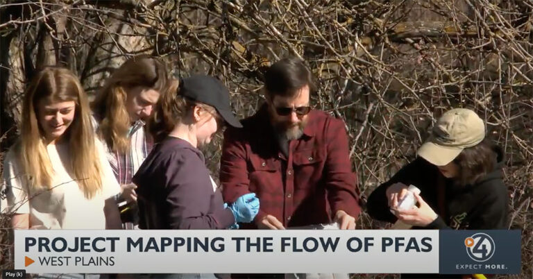 Students gathered around water testing samples with their professor.