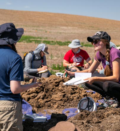 students taking notes and discussing at the prairie site on a warm day