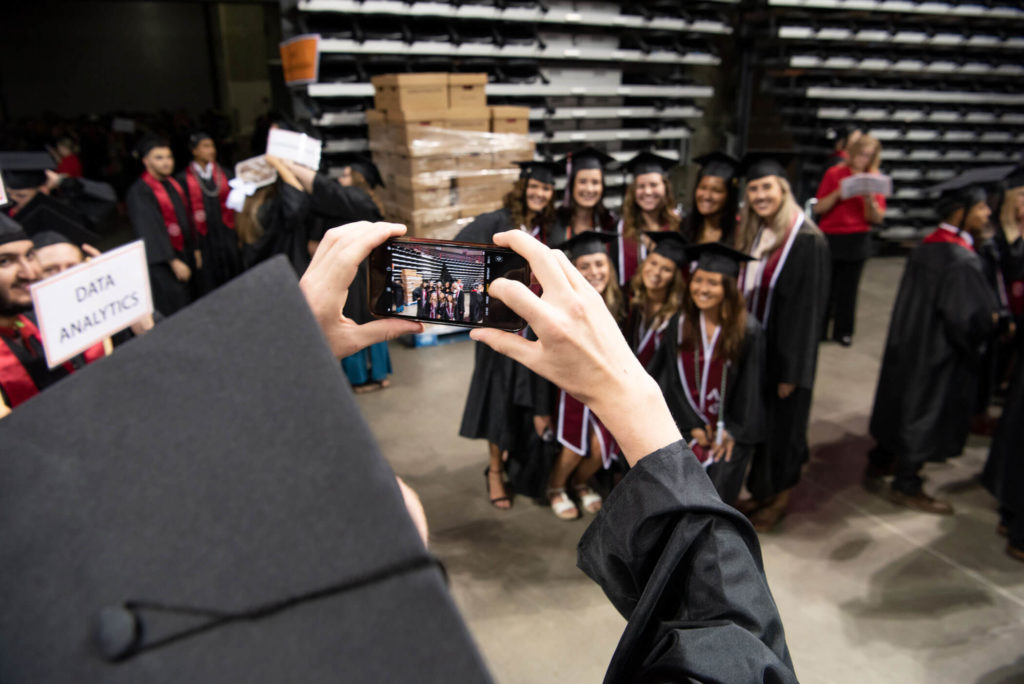 A group of students huddle for a photo backstage at Commencement
