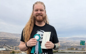 Student holding a ribbon and scholarship envelope.