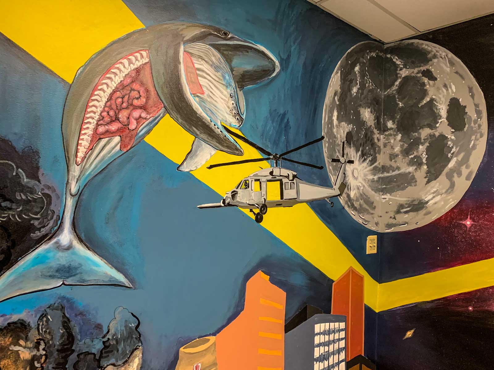 Painted mural in the entryway of the Science Building featuring the moon, a whale, buildings and a helicopter
