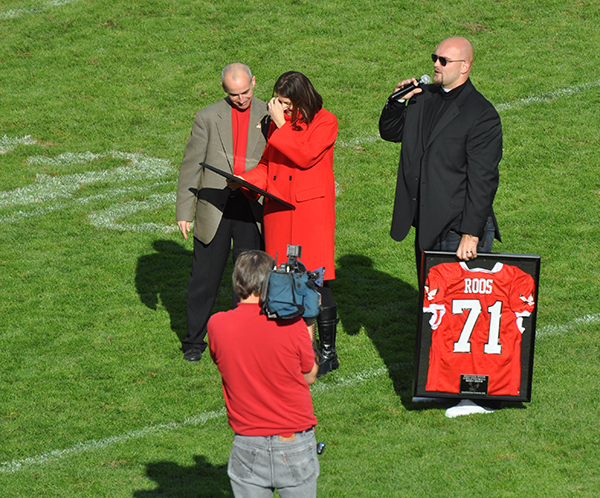 Michael Roos standing on the centerfield holding a framed jersey
