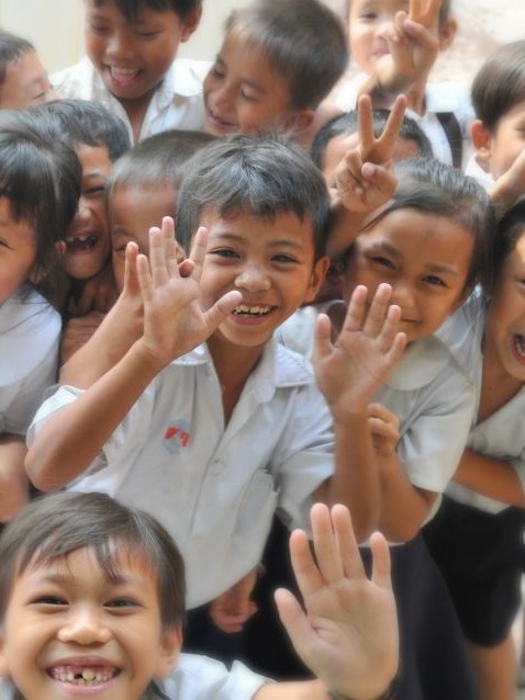 Vertical image of group of laughing and waving school age children.