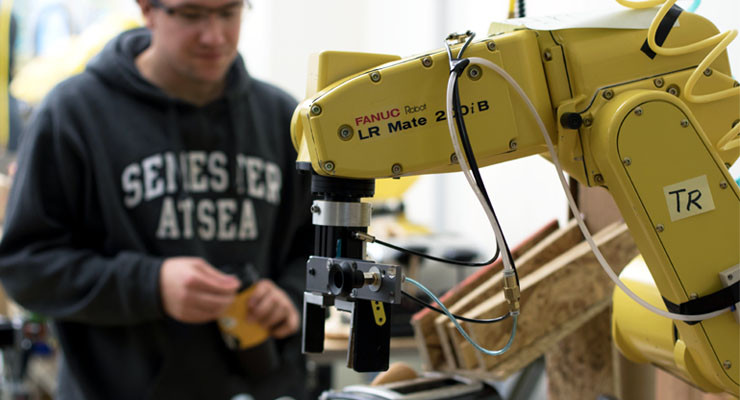 Photo: Student working with a yellow mechanical arm