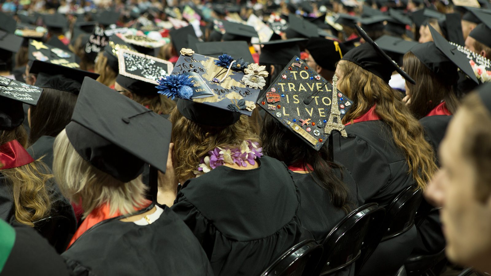 Photo: Students sitting at commencement with decorated graduation caps