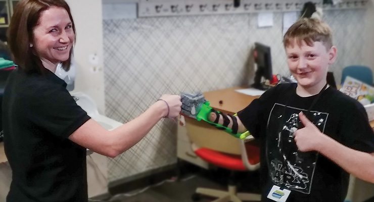 picture: student and boy with prosthetic arm fist bump