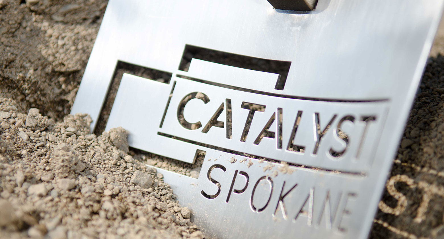 Photo: Shovel with words "CATALYST SPOKANE" digging into dirt