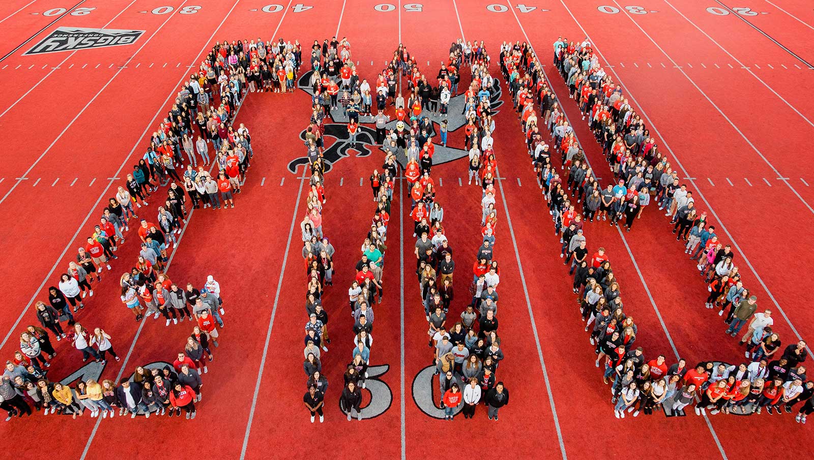 Students from the class of 2022 assemble to form the letters "EWU" on the red turf of Roos Field