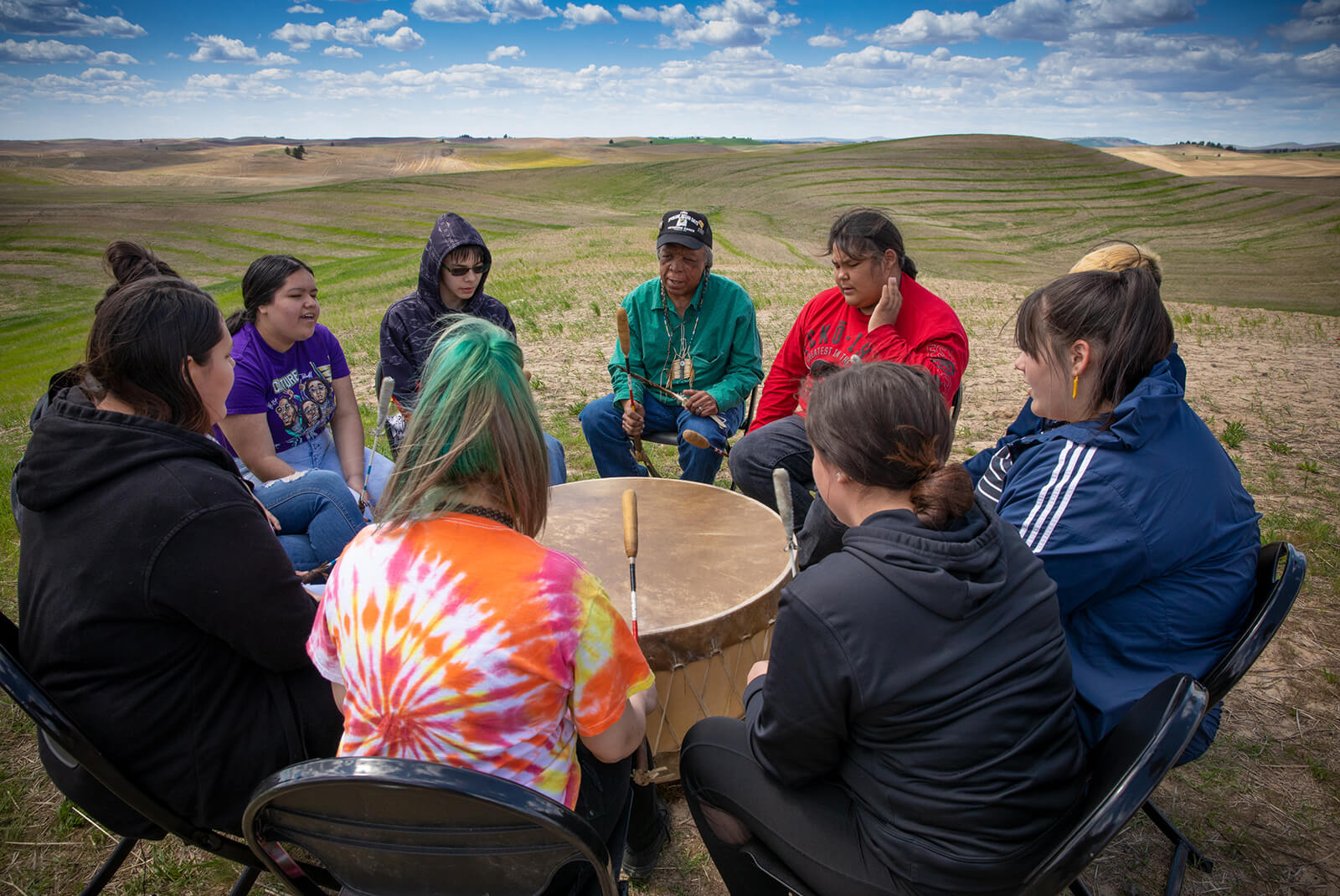 Members of the drum circle gather around the drum on the edge of the prairie