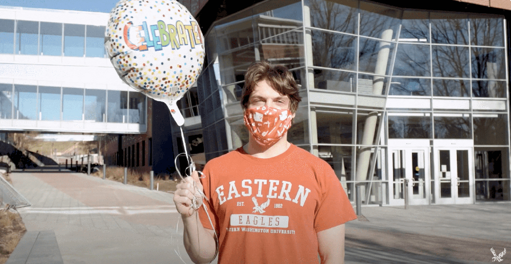 Student wearing a Eastern shirt holding a balloon wearing a mask.