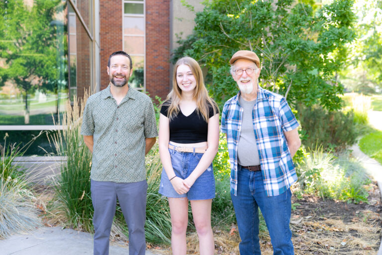 Two geoscience professors standing with a student award winner