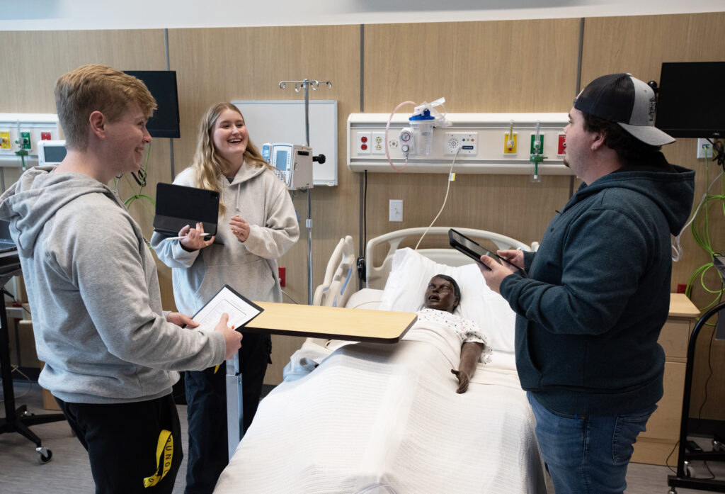 Nursing students practicing on simulation station with dummy