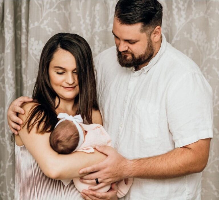Lauren and Ryan Poynter, holding their infant daughter.