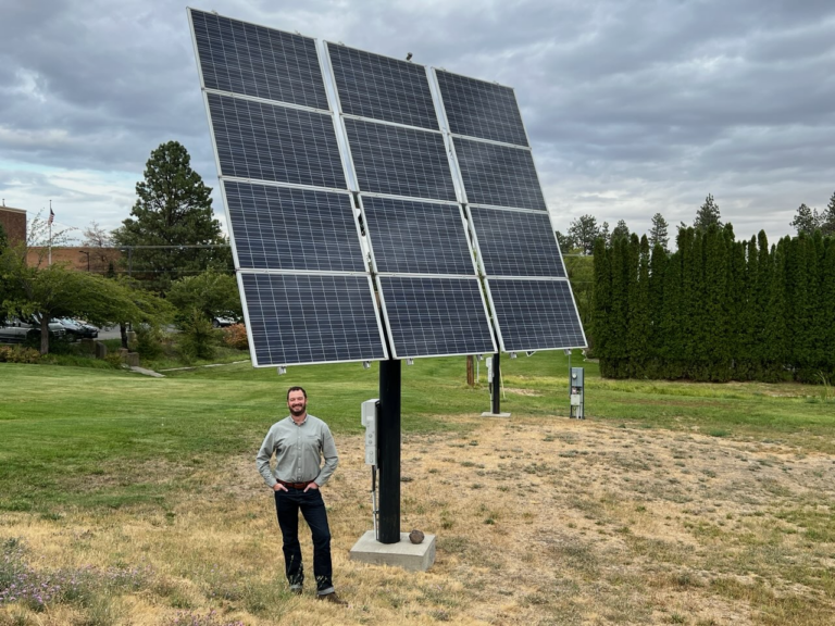 Erik Budsberg standing in front of a large solar panel.