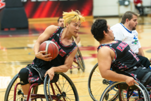 Three wheelchair athletes playing basketball.