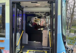 Swoop the mascot is pretending to drive the bus.