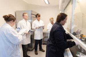 Alumna teaching students how to test compounds.