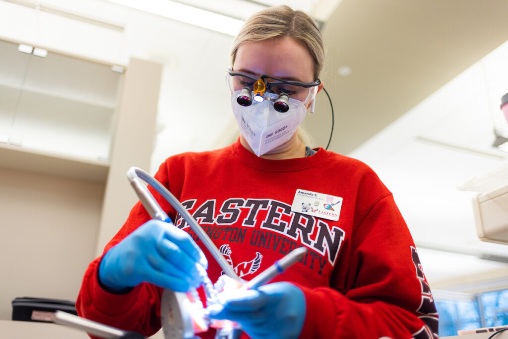 Dental hygiene student using tools to work on teeth.