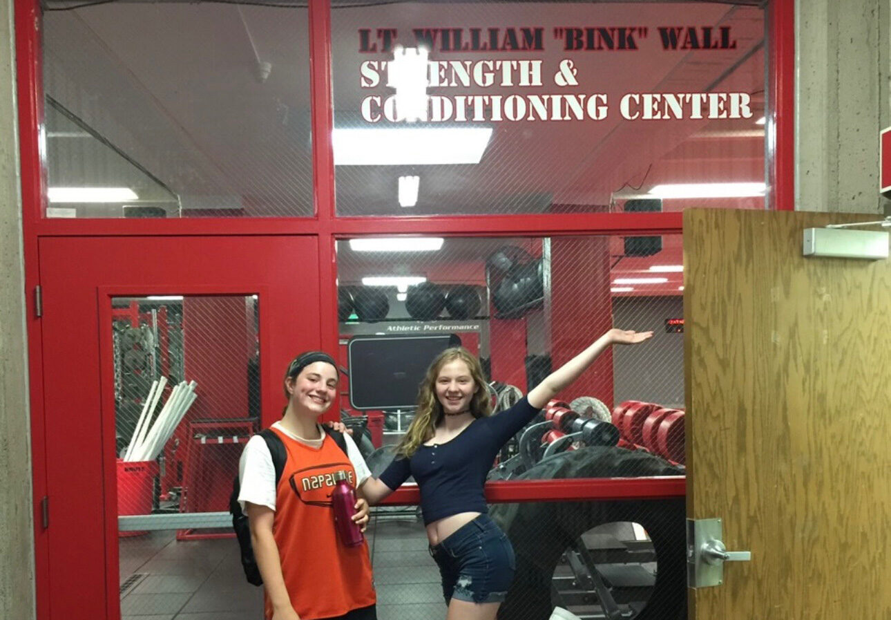 Photo of Bink's two granddaughters in front of the Strength and Conditioning Center names after him.