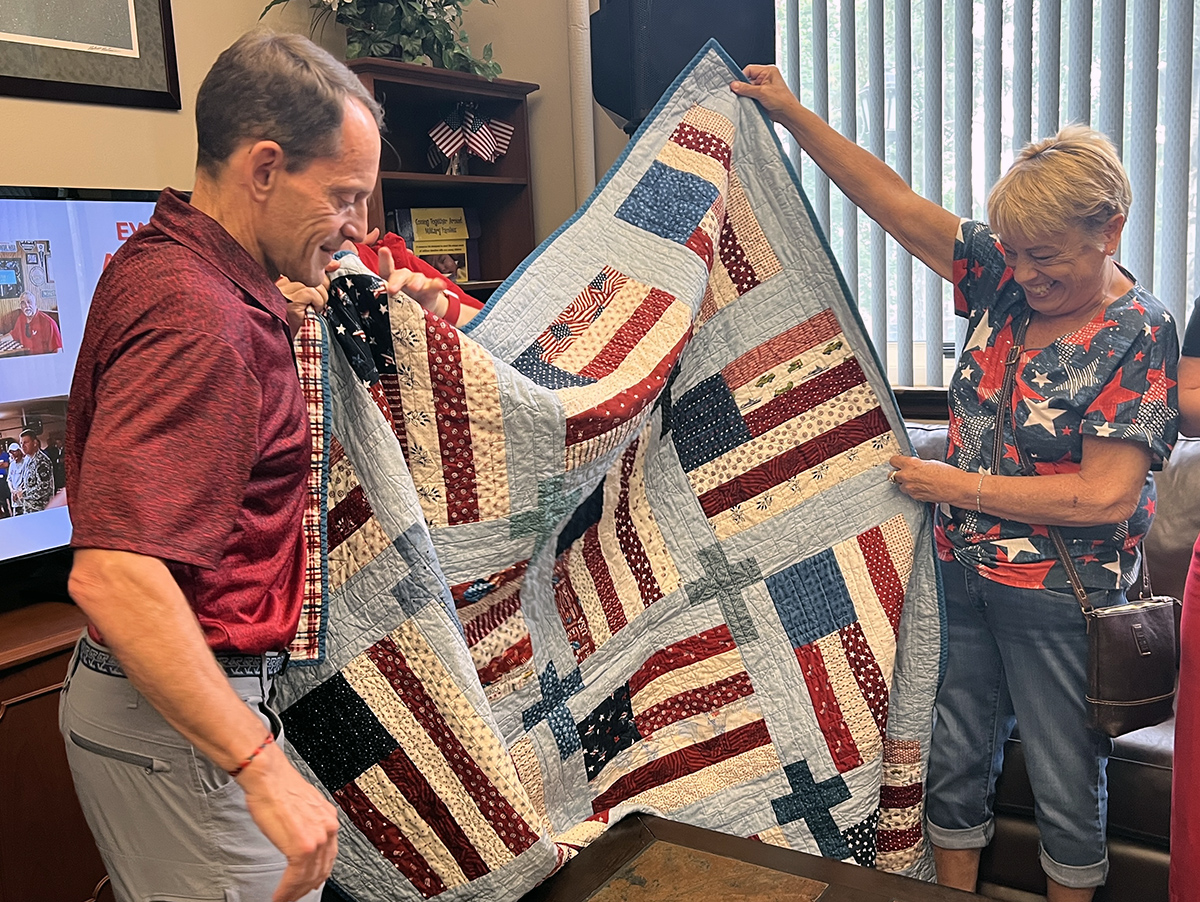 Dave Millet receives a handmade quilt from an alumna.
