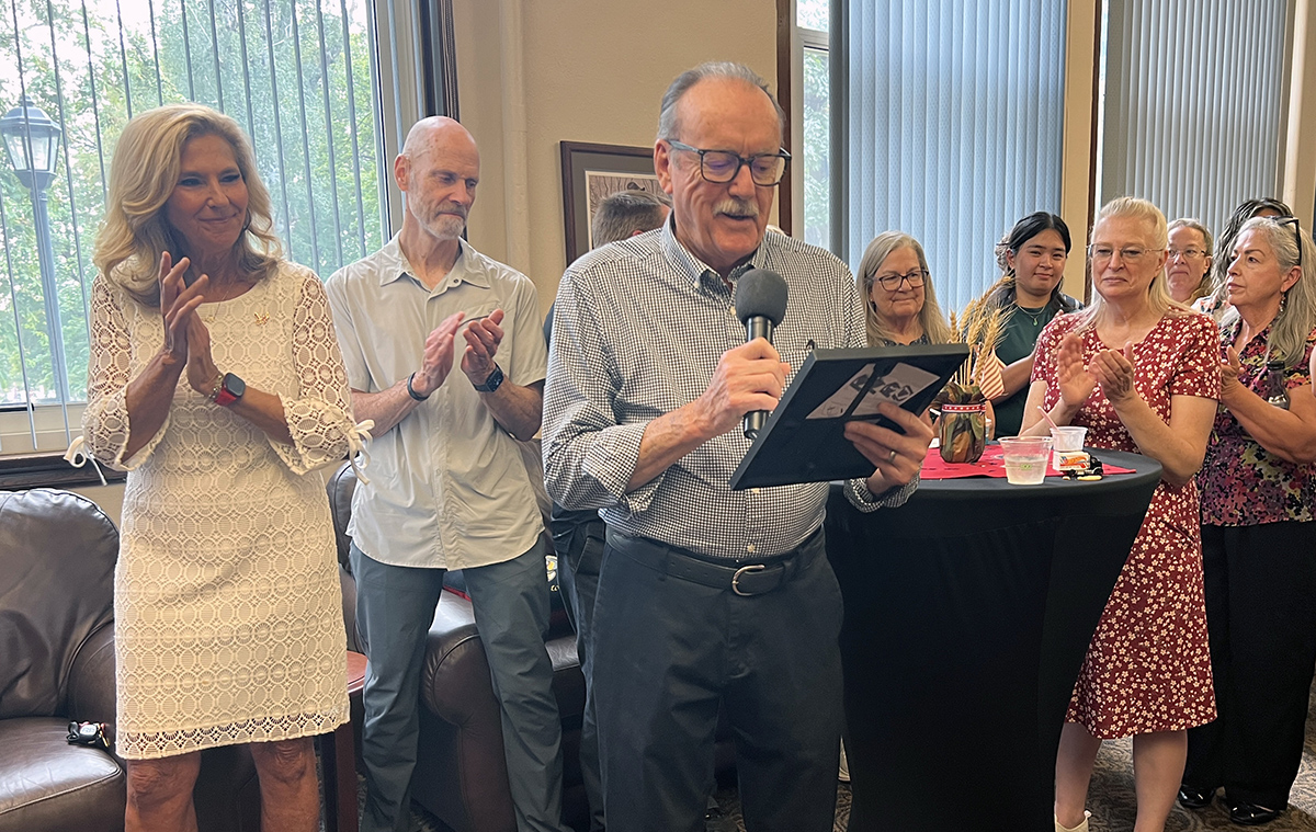 Alan Basham speaking about leadership and holding a plaque for Dave Millet.