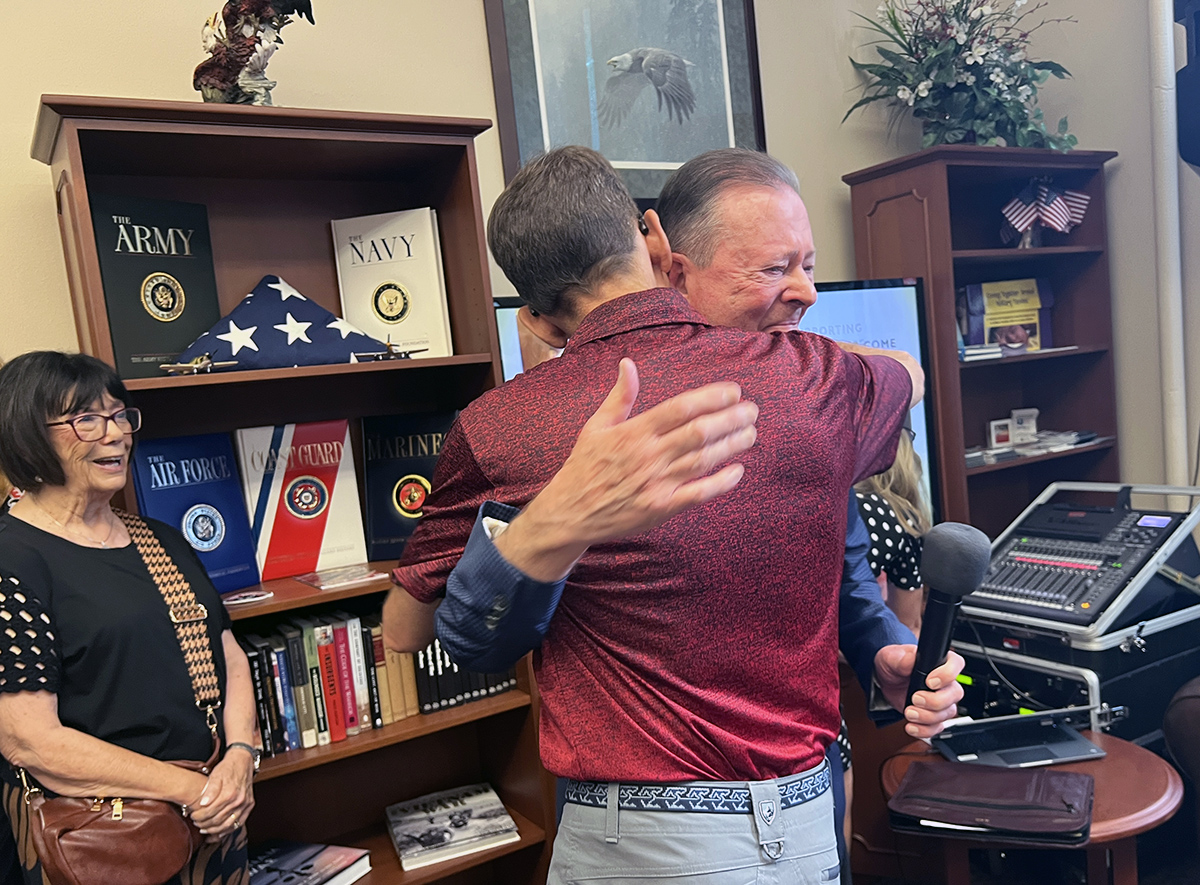 Dave Millet hugging Bill Cross after the gift announcement. Connie Cross is smiling in the background.