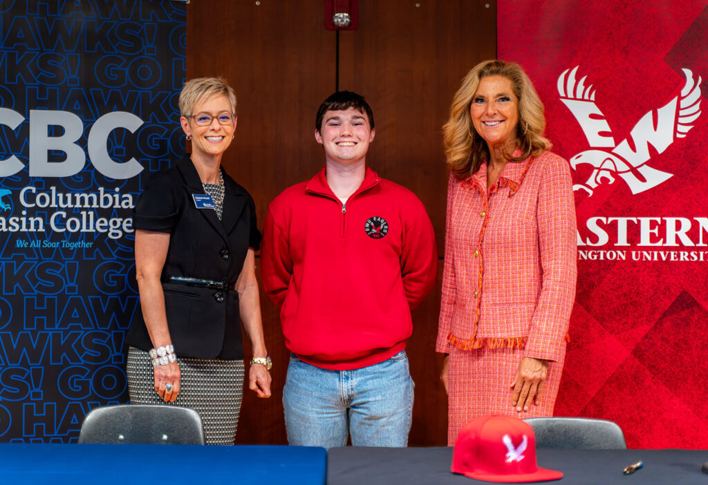 University presidents stand with student at ceremony.