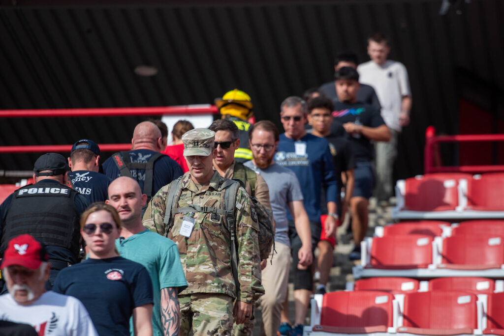 Photo of campus community climbing steps at Roos Field. Some are police and ROTC.