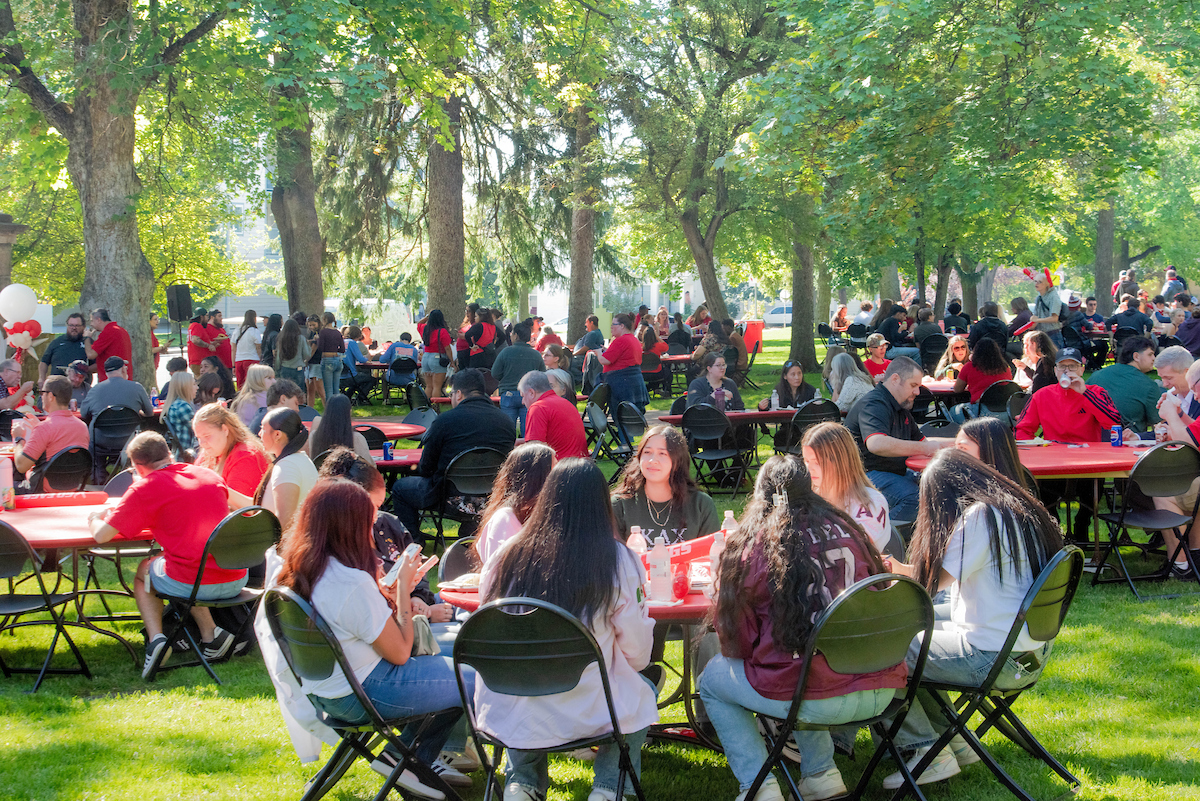 Students sitting at a table for the Pass Through the Pillars picnic.