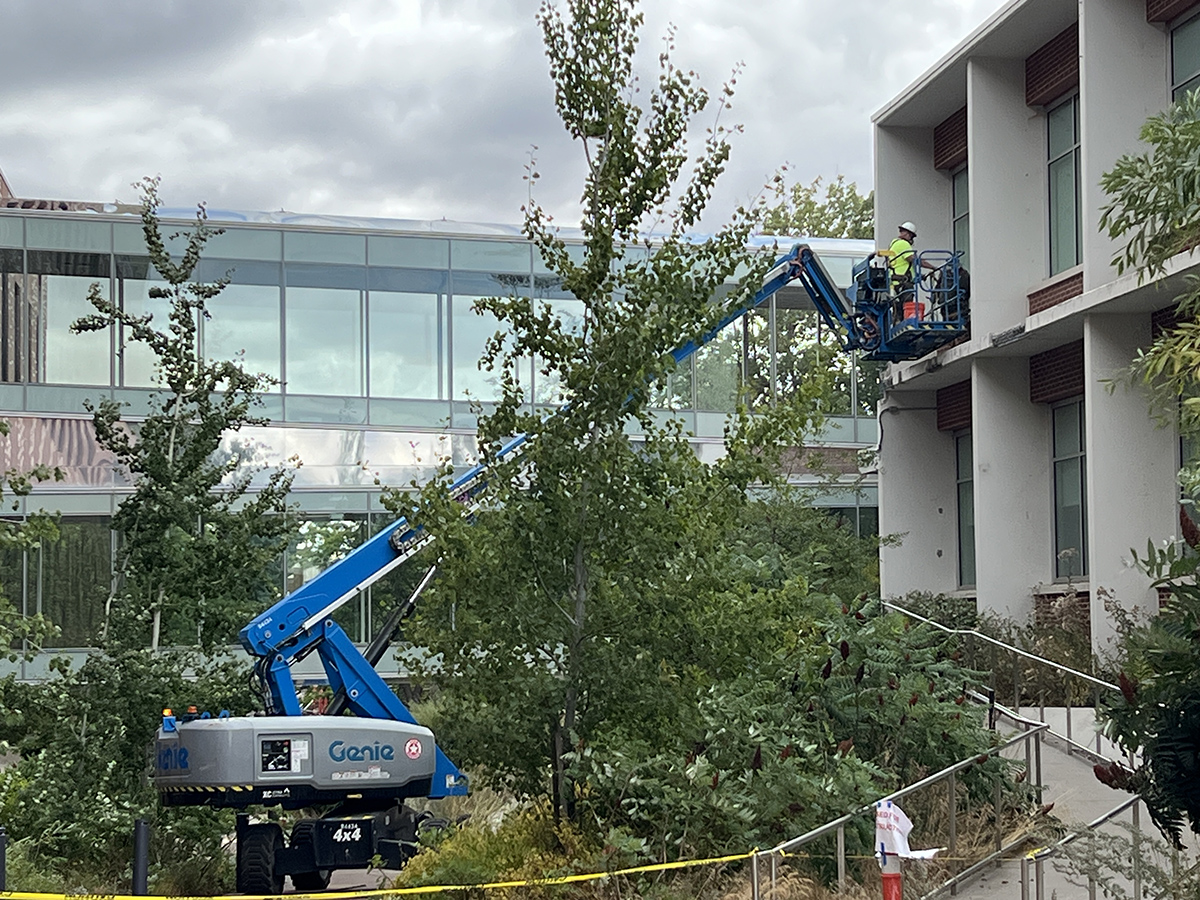 Picture of boom lift with construction worker working on second floor window.