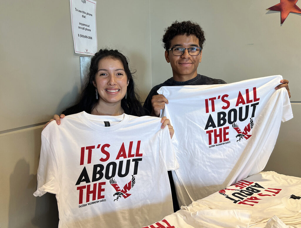 Two students hold up the free "It's all about the Eagle" T-shirts for students.