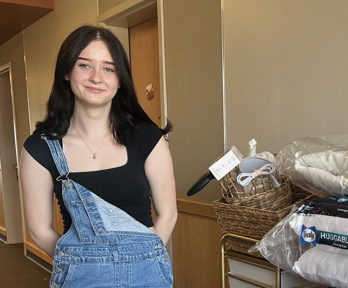 Student with her belongings stacked near her dorm room door.