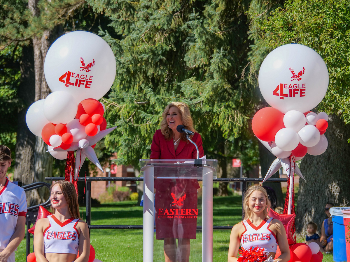 President Shari McMahan speaking at the podium with balloons on the side.